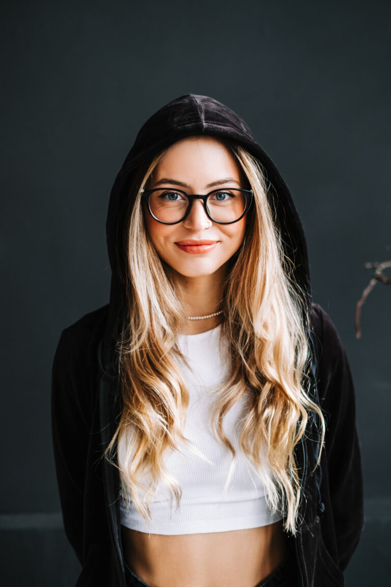 Portrait of young attractive cheerful woman in a hood looking on camera over black background.